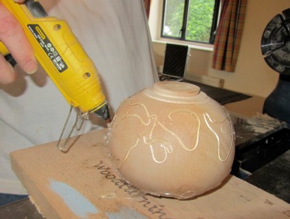A hollow form being decorated using hot melt glue
